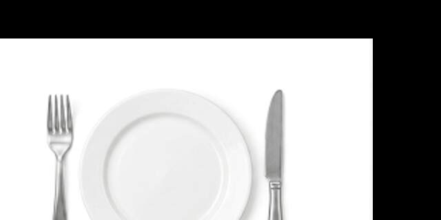 Assiette blanche avec couverts en métal sur fond blanc